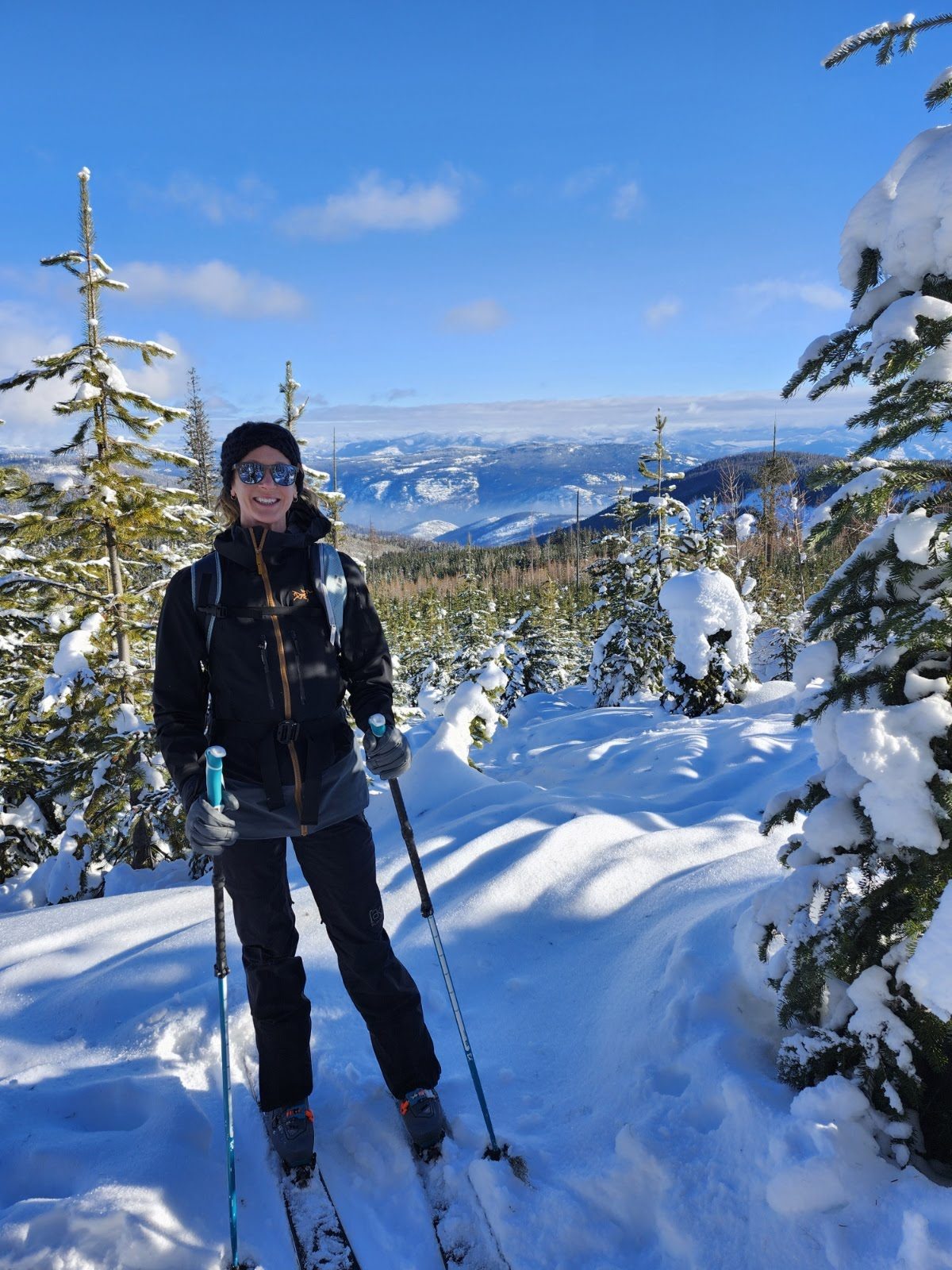 Tara cross-country skiing on a groomed trail in winter, the valley behind her.